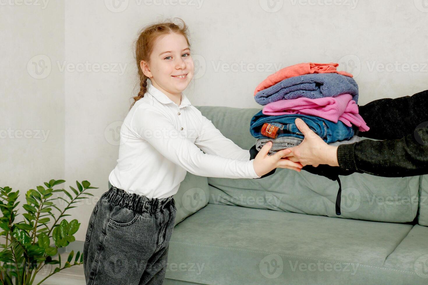 meisje ontvangt een stack van kleren net zo een geschenk, liefdadigheid foto