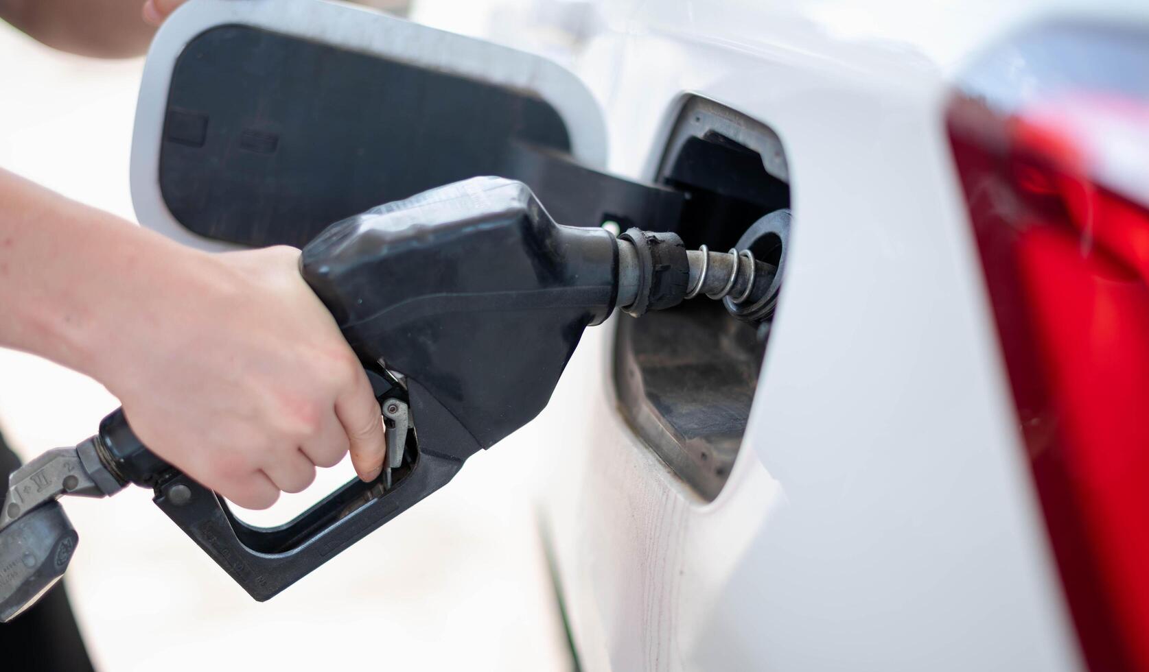 vrouw arbeider hand- Holding mondstuk brandstof vullen olie in auto tank Bij pomp gas- station foto