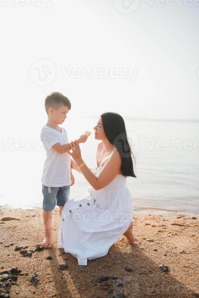 moeder en zoon wandelen Aan zonsondergang strand foto