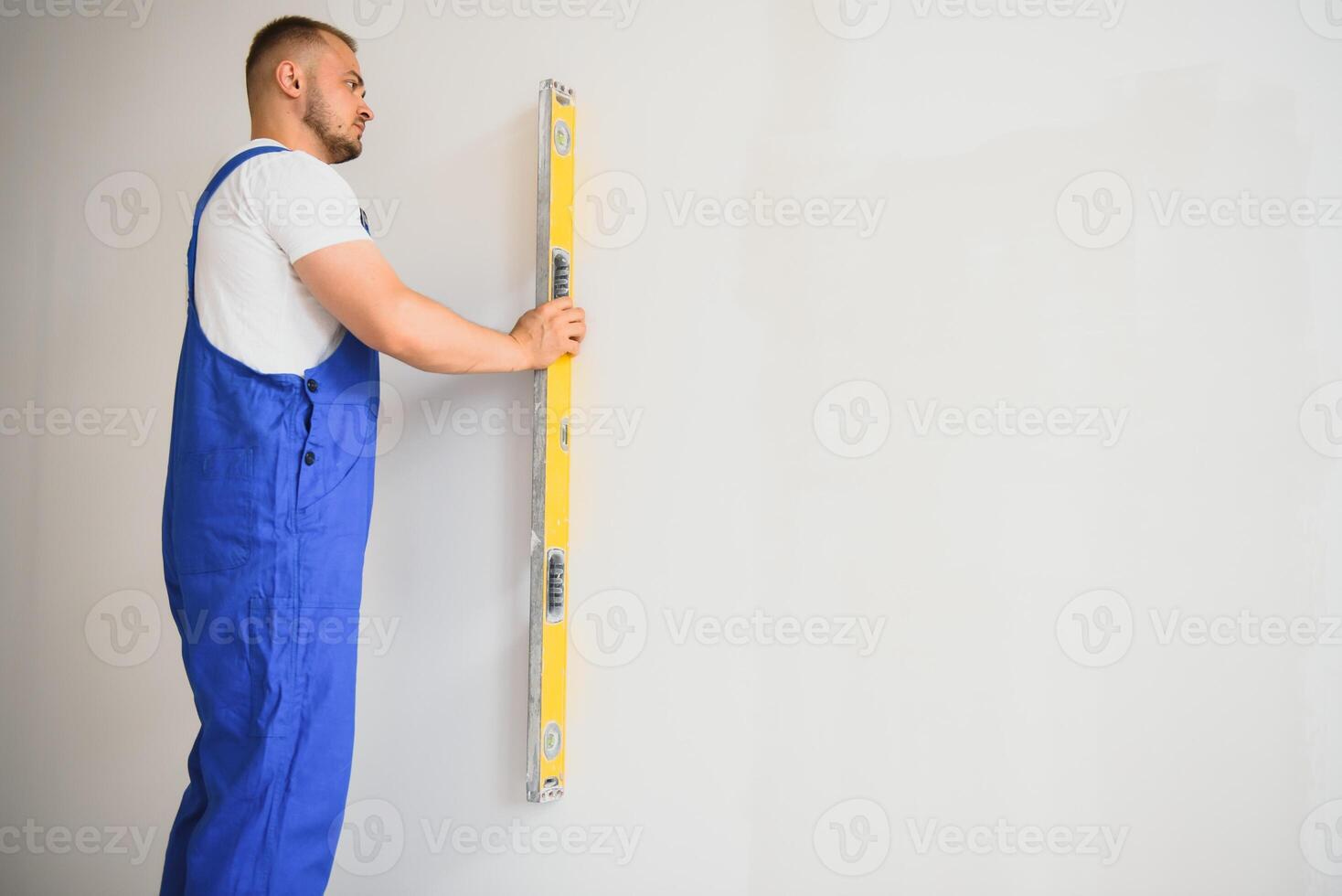 portret van jong specialist maken muur vlak in nieuw gebouw foto