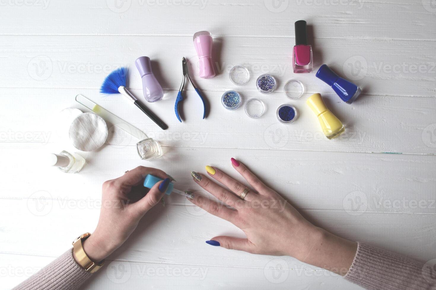 een vrouw schilderij haar nagels. gereedschap voor manicure Aan een wit houten tafel. foto