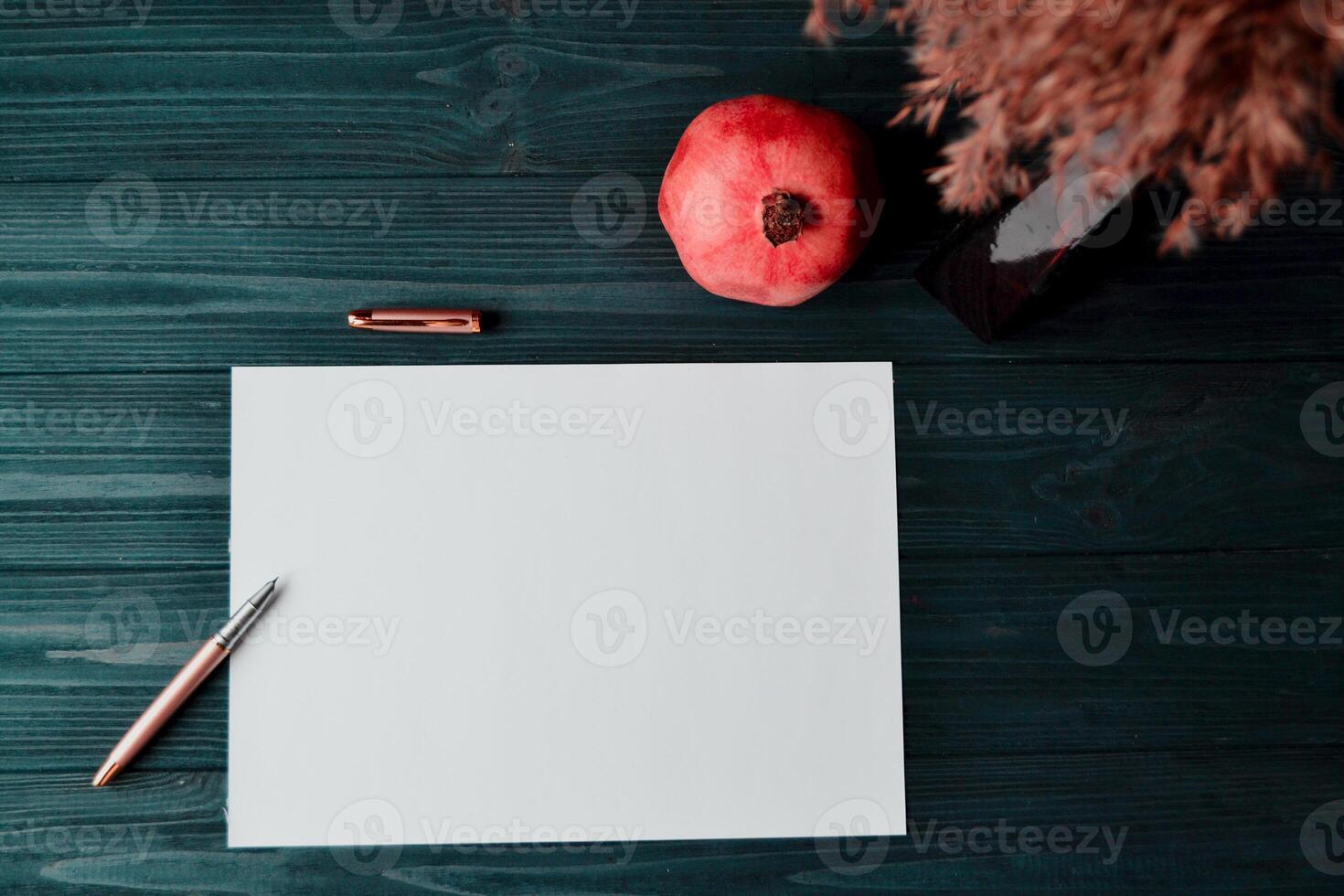 de vel van wit papier met pen en granaat Aan de donker blauw houten bureau. wijnoogst achtergrond met plaats voor tekst. foto