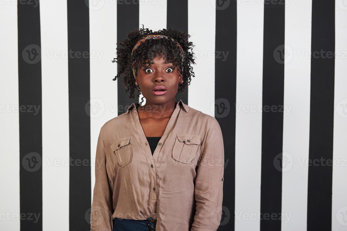 wat slecht nieuws. mooi vrouwelijk portret op de zwarte en blauwe strepen type achtergrond. Afro-Amerikaans meisje trekt geschokt gezicht foto
