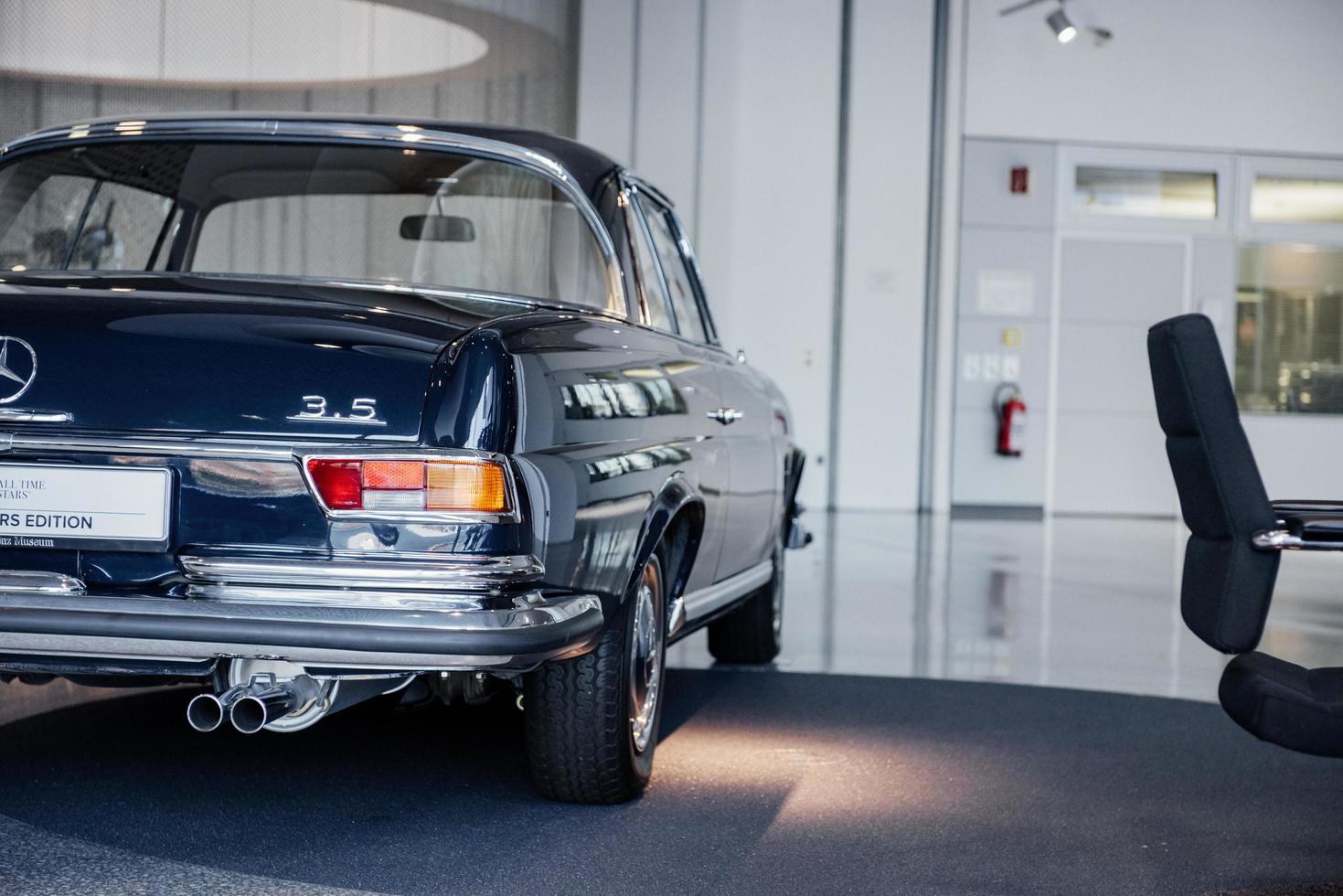 stuttgart, duitsland - 16 oktober 2018 mercedes museum. klassieke blauwe auto geparkeerd in de buurt van de stoel. van achteren vastgelegd foto