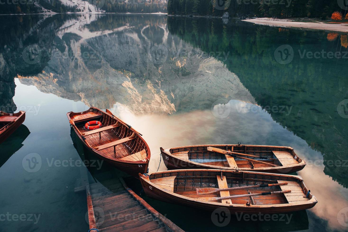 kom gewoon binnen en zwem. houten boten op het kristalmeer met majestueuze berg erachter. weerspiegeling in het water foto