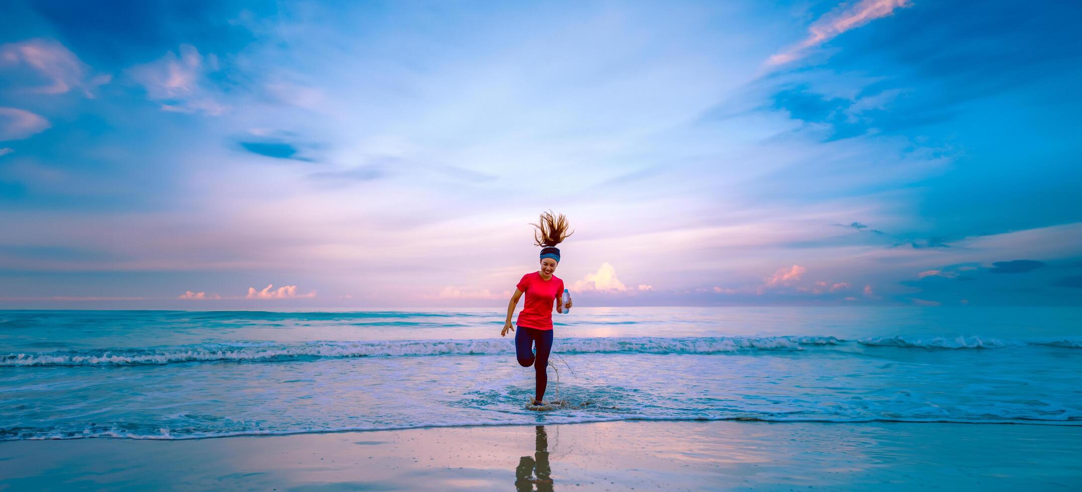 meisje met training joggen op het strand in de ochtend. ontspannen en blij zijn met hardlopen op zee. in de zomer foto