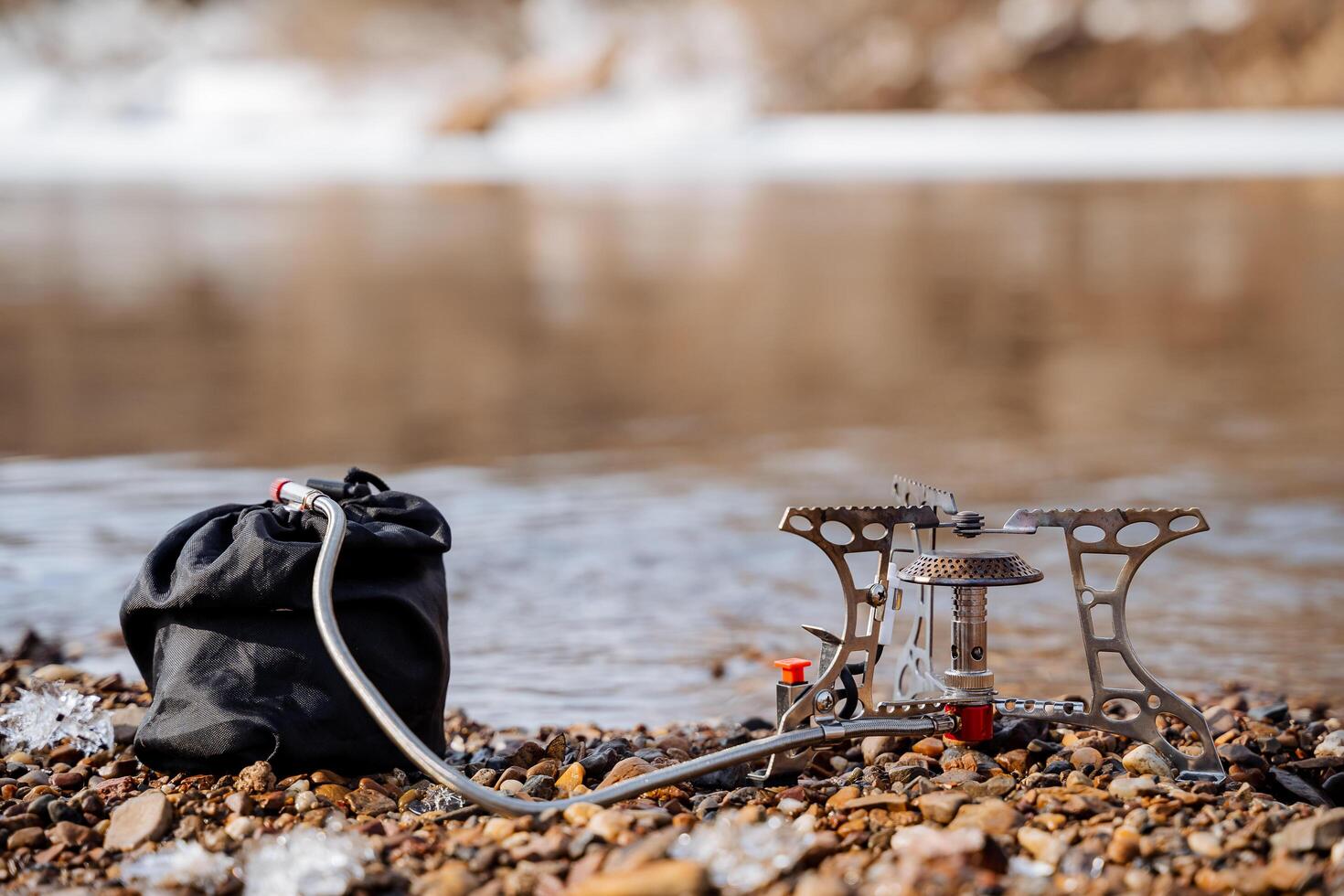 een toerist brander staat Aan rotsen tegen de achtergrond van de rivier, een gas- brander met een slang en een gas- cilinder, de concept van camping uitrusting voor een wandeltocht. foto