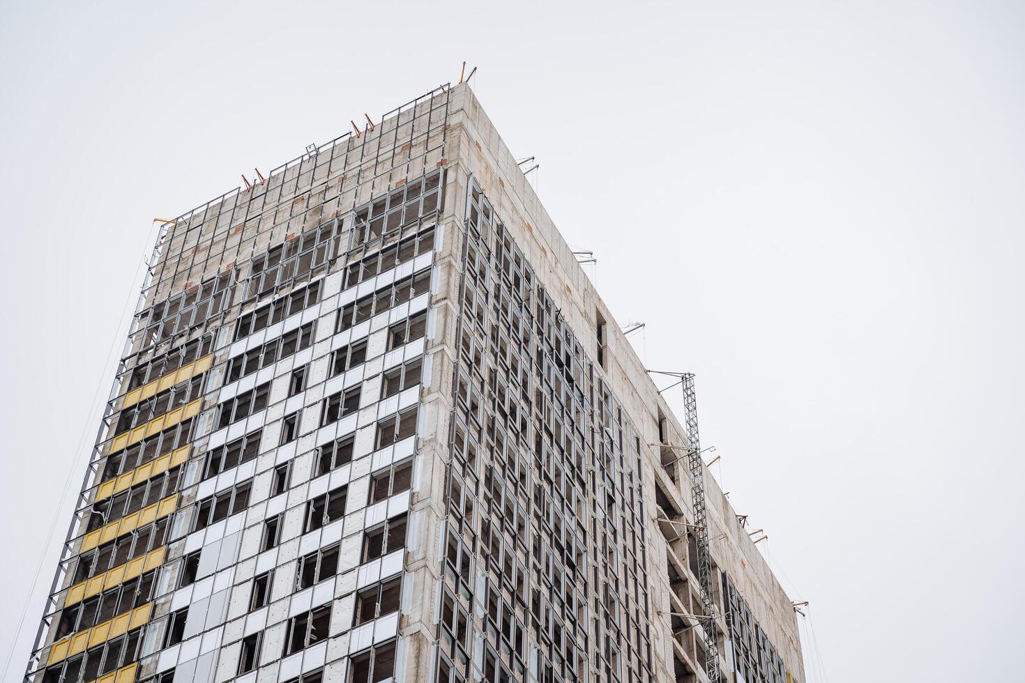 visie van de gebouw tegen de achtergrond van de lucht bouw van een wolkenkrabber. afwerking werken van de facade van de woon- gebouw. beton muren zijn staal krat. appartement complex. foto