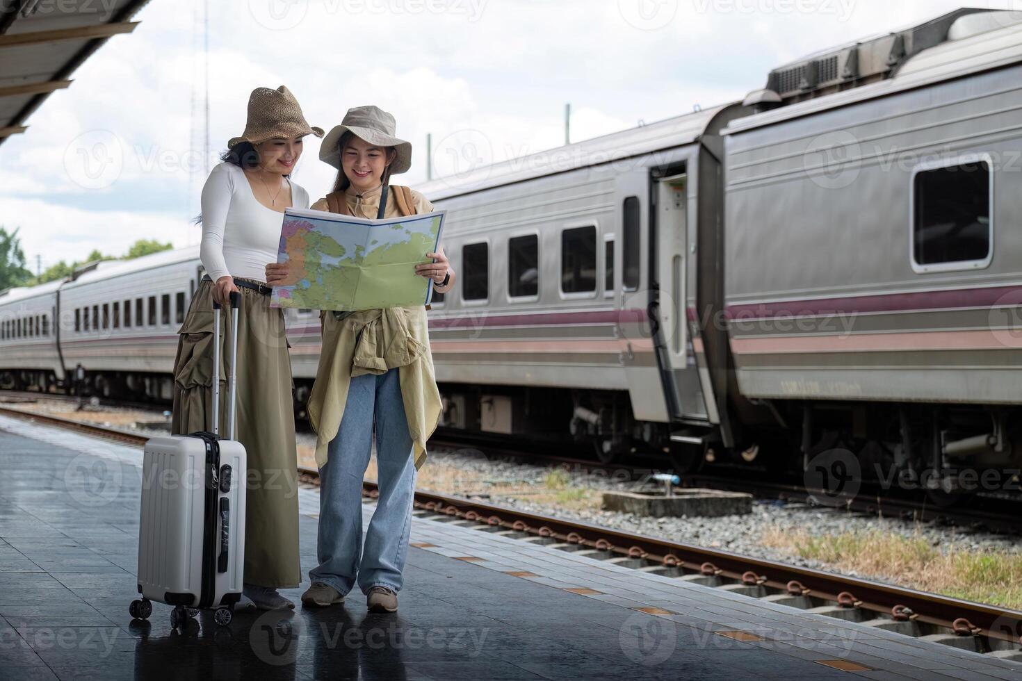 reizen concept. meisje vriend slijtage hoed Holding kaart hebben zak en bagage. vrouw reiziger aan het wachten trein Bij trein station foto