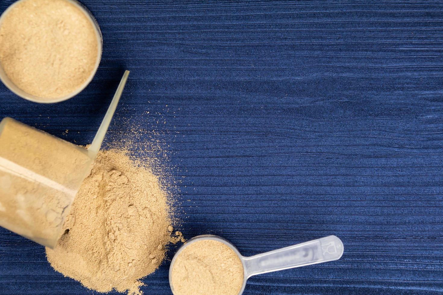 bolletjes gevuld met eiwitpoeders op blauw hout als achtergrond foto