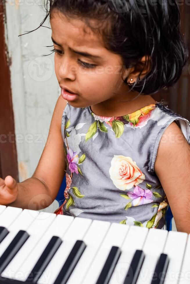 Aziatisch schattig meisje spelen de synthesizer of piano. schattig weinig kind aan het leren hoe naar Speel piano. kind handen Aan de toetsenbord binnen. foto