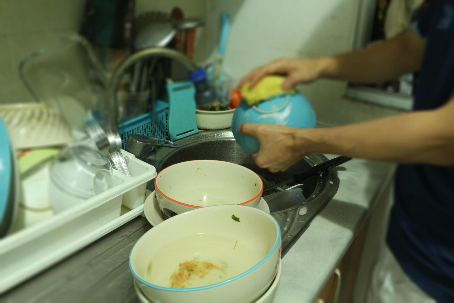 dichtbij omhoog handen van mannen het wassen gerechten en cups in de keuken. foto