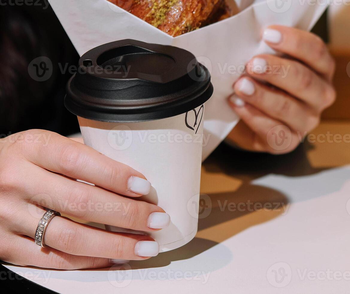 meisje aan het eten croissant met pistache poeder en drinken koffie Aan terras foto