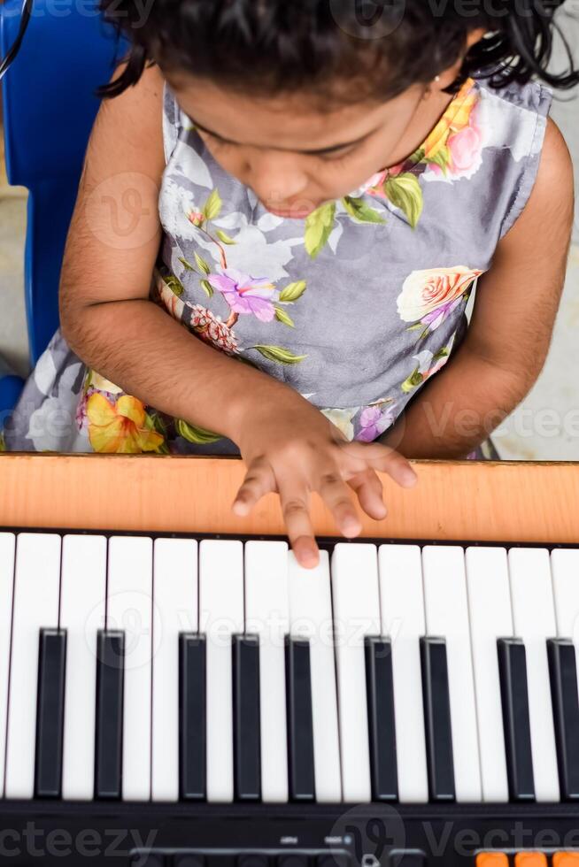 Aziatisch schattig meisje spelen de synthesizer of piano. schattig weinig kind aan het leren hoe naar Speel piano. kind handen Aan de toetsenbord binnen. foto