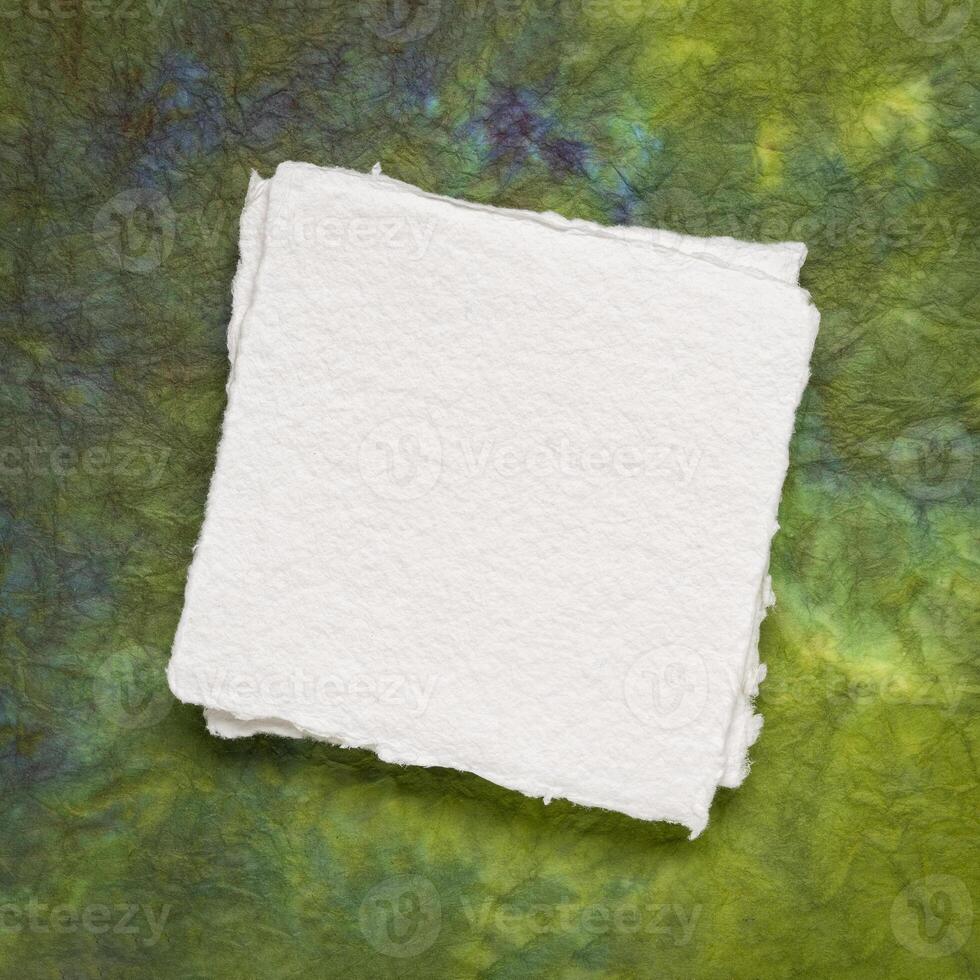 klein plein vel van blanco wit khadi papier tegen kleurrijk gemarmerd papier foto