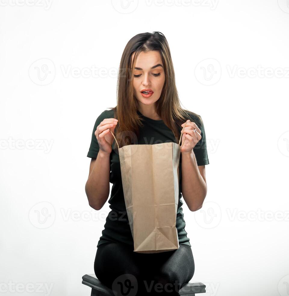 vrouw Holding kruidenier boodschappen doen zak Aan wit achtergrond. jong meisje is op zoek in licht bruin boodschappen doen tas. geïsoleerd achtergrond. detailopname. foto