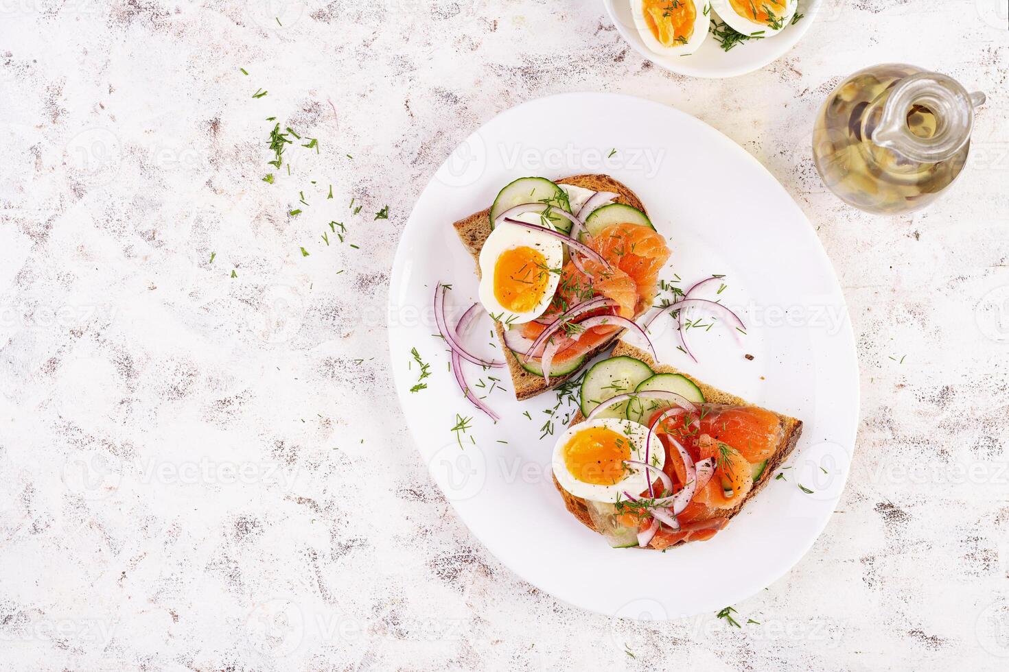 heerlijk geroosterd brood met Zalm, gekookt ei, komkommer en room kaas Aan een wit bord. gezond aan het eten, ontbijt. keto eetpatroon voedsel. smakelijk voedsel. top visie foto