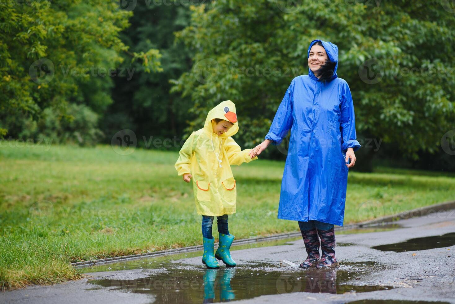 moeder en kind, jongen, spelen in de regenen, vervelend laarzen en regenjassen foto