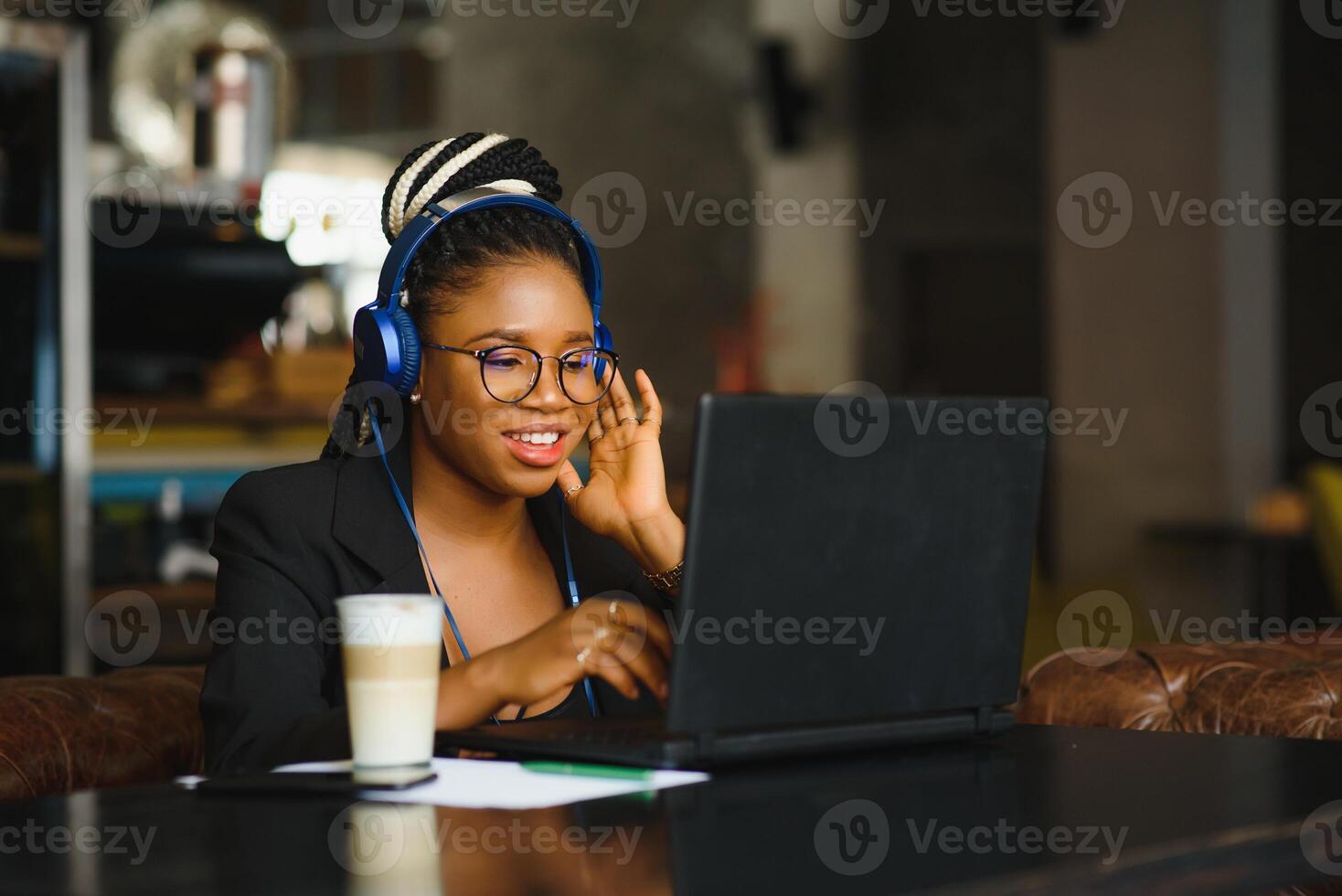jong Afrikaanse Amerikaans meisje zittend Bij cafe tafel met laptop en op zoek Bij scherm. donker huid freelancer concept. foto