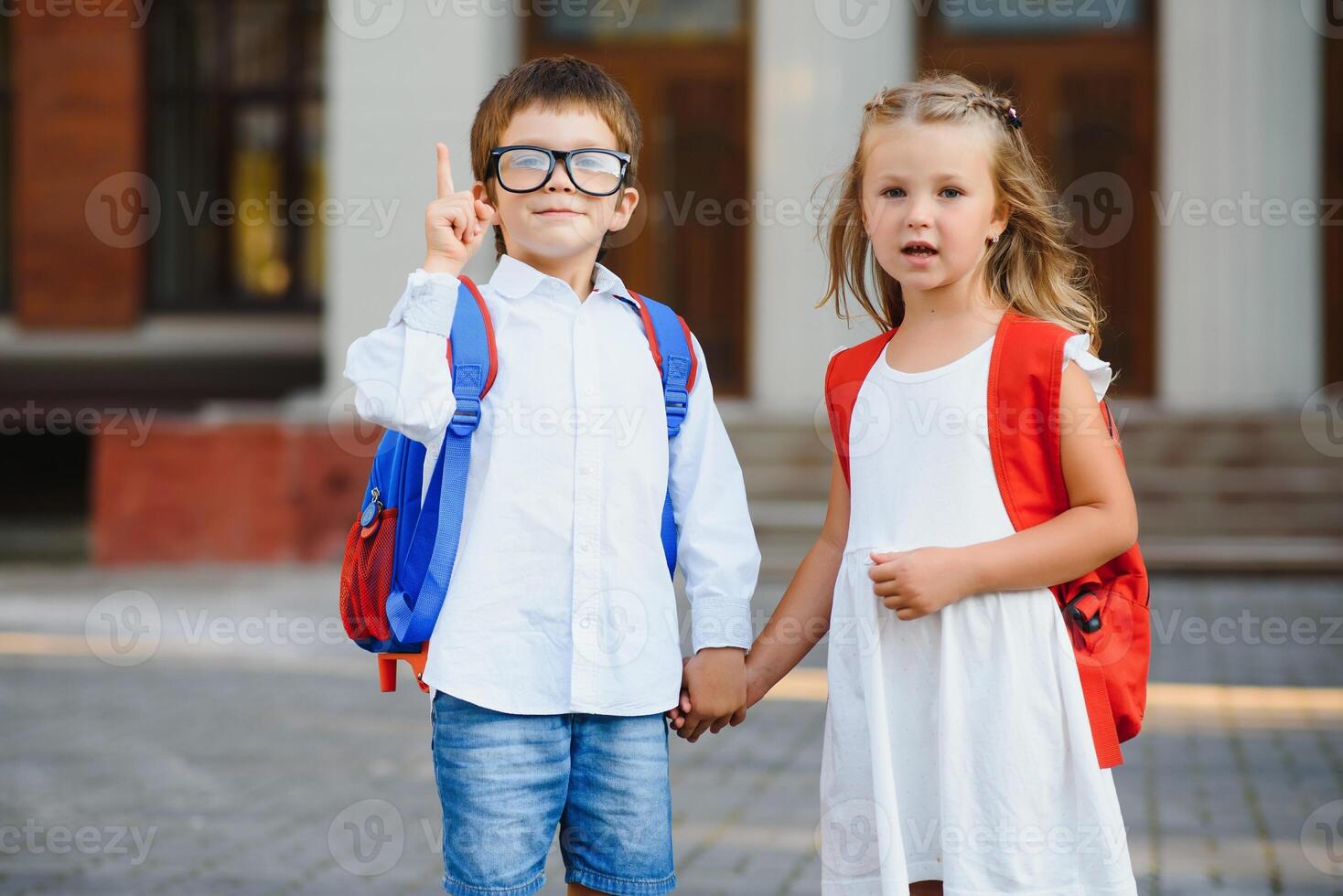 gelukkig kinderen Gaan terug naar school. leerling van primair school- Gaan studie met rugzak buitenshuis. kinderen Gaan hand- in hand. begin van lessen. eerste dag van val. jongen en meisje van elementair leerling. foto