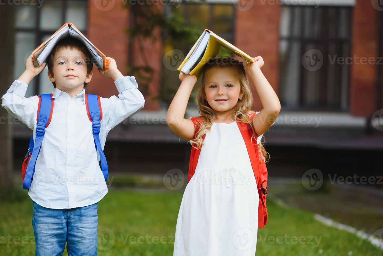gelukkig kinderen - jongen en meisje met boeken en rugzakken Aan de eerste school- dag. opgewonden naar worden terug naar school- na vakantie. vol lengte buitenshuis portret. foto