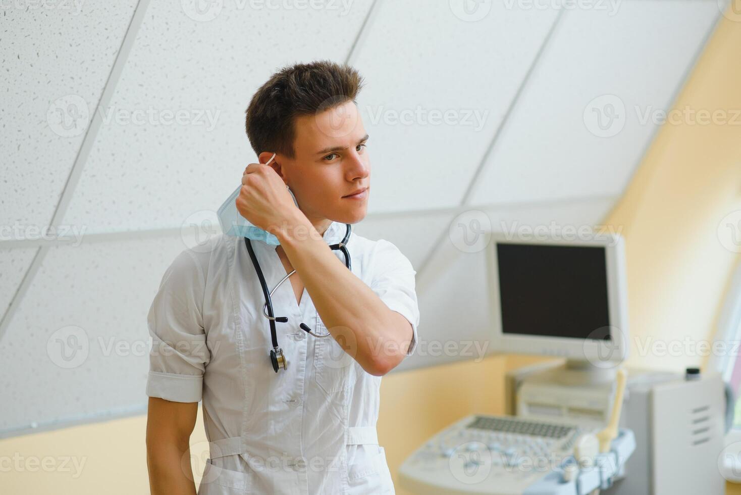 mannetje dokter in masker met echografie uitrusting in de kliniek kantoor foto