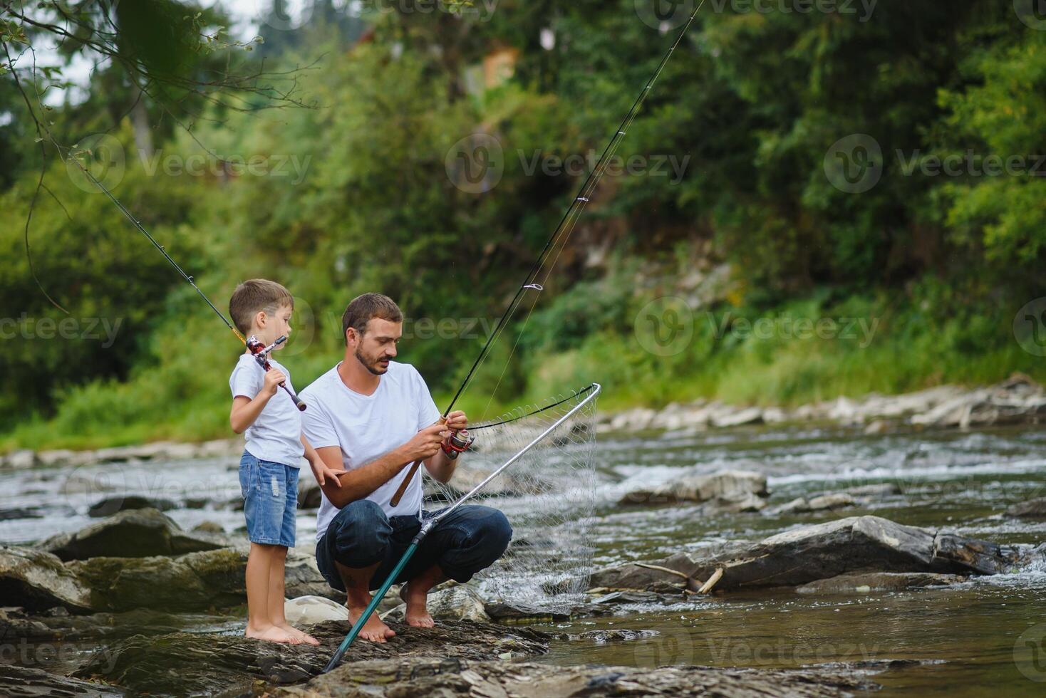 een vader onderwijs zijn zoon hoe naar vis Aan een rivier- buiten in zomer zonneschijn foto