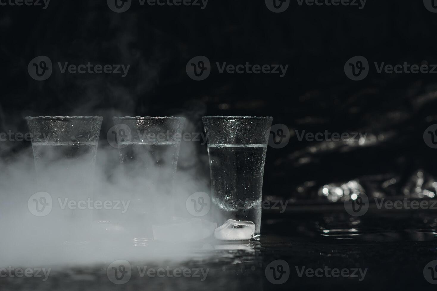 wodka schoten met ijs Aan zwart tafel, kopiëren ruimte. foto