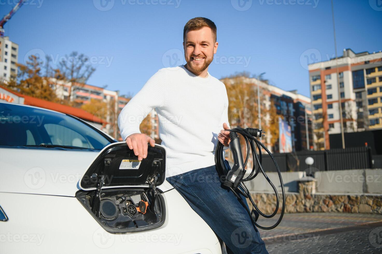 Mens kosten een elektrisch auto Bij de opladen station foto