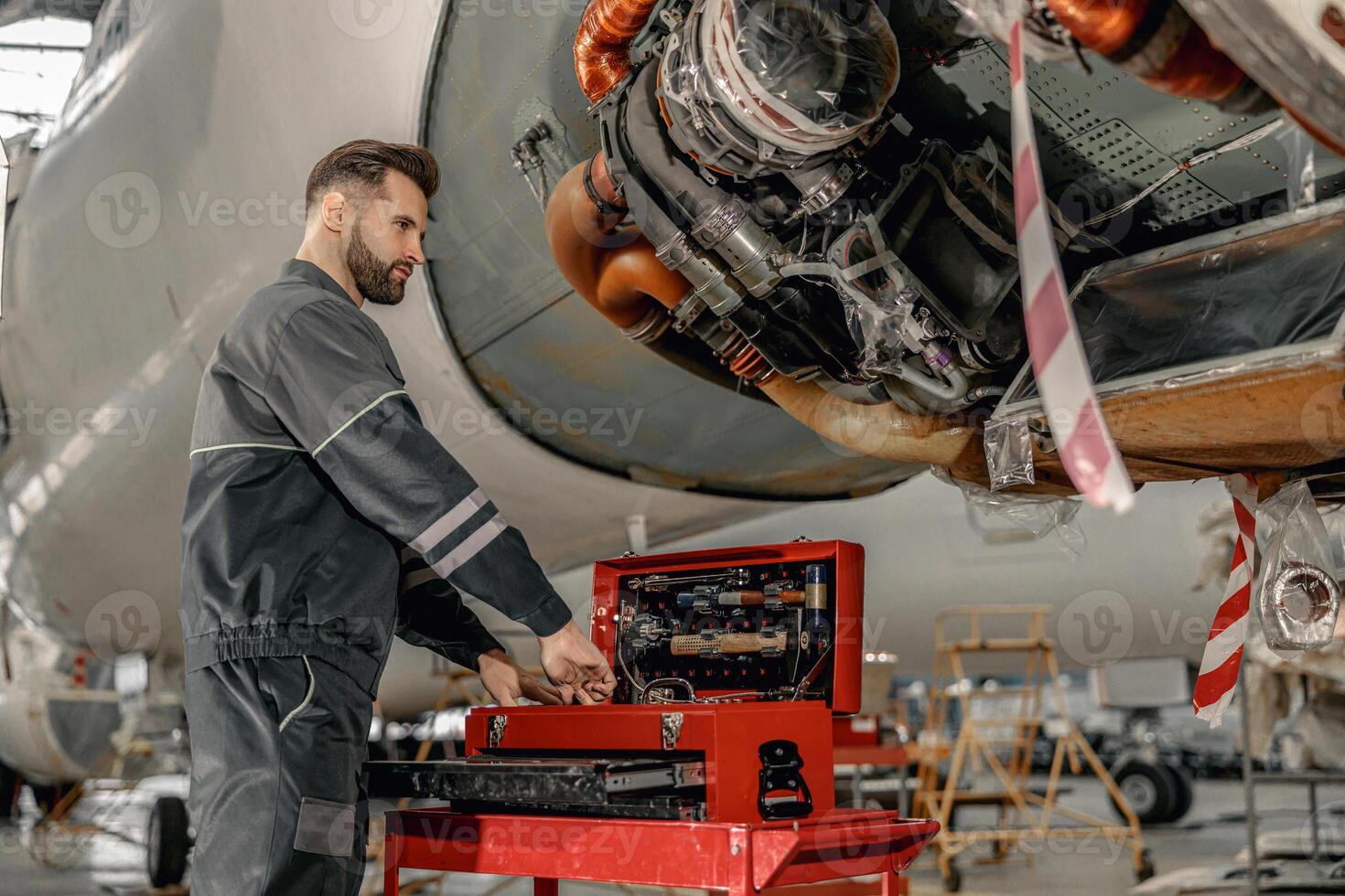 gebaard Mens vliegtuig monteur gebruik makend van instrument doos in hangar foto