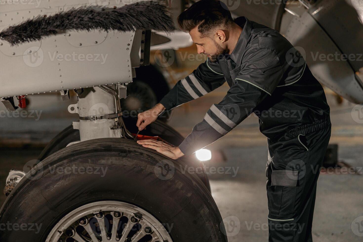 mannetje luchtvaart monteur repareren vliegtuig wiel in hangar foto