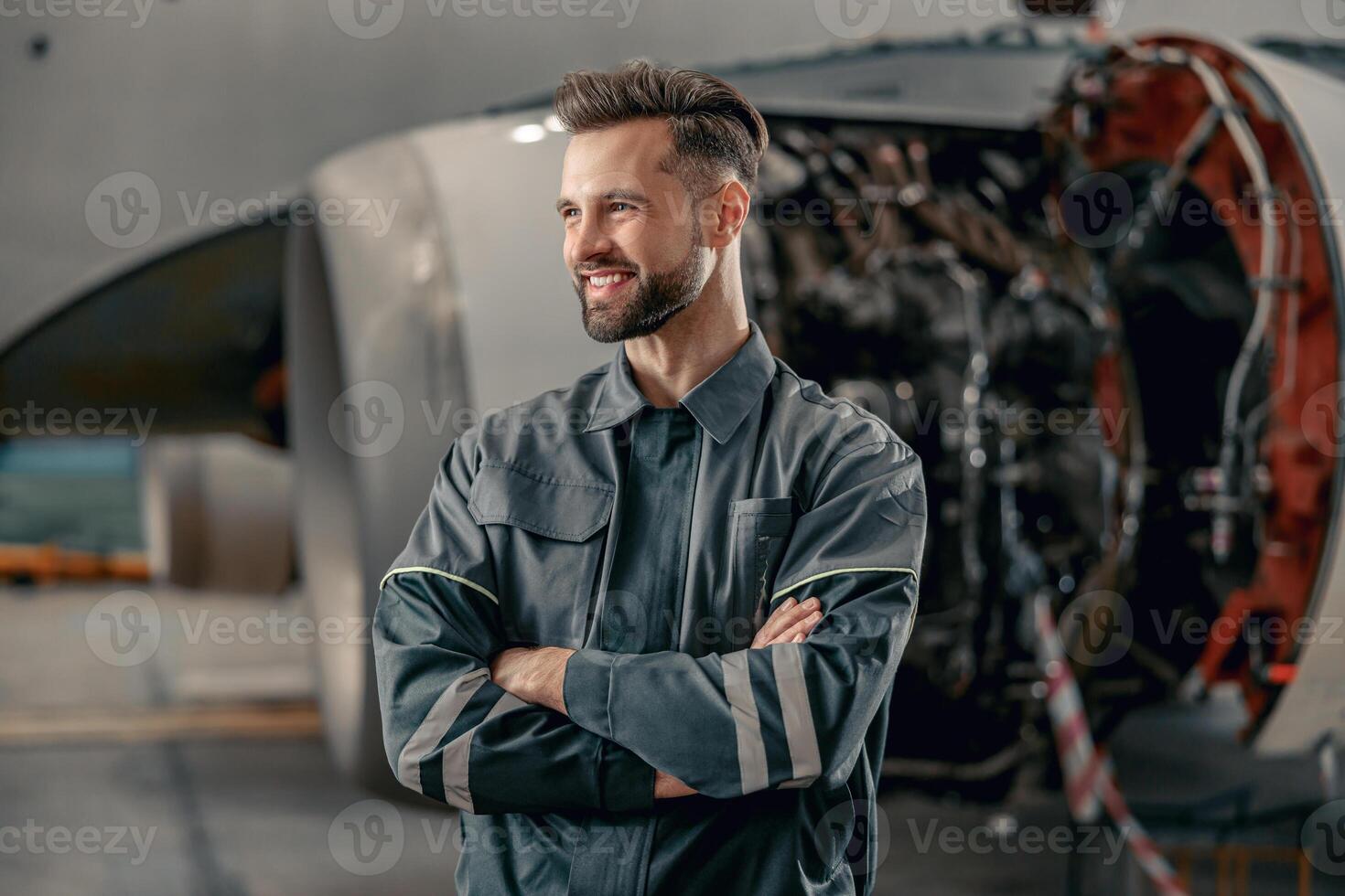 vrolijk vliegmaatschappij monteur staand in de buurt vliegtuig in hangar foto