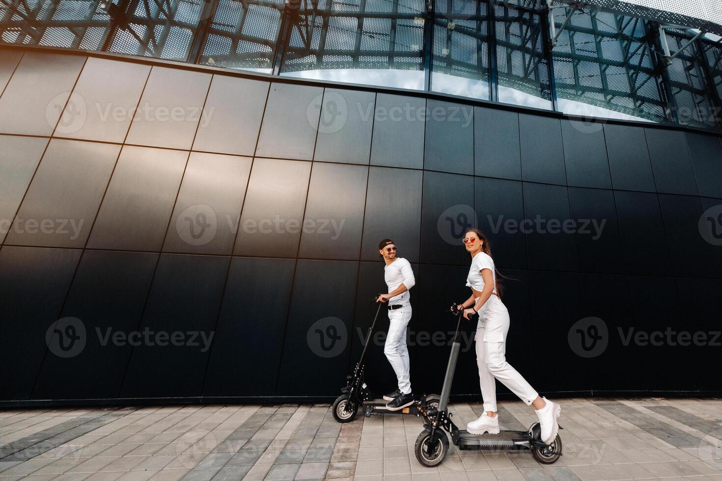 een meisje en een vent zijn wandelen Aan elektrisch scooters in de omgeving van de stad, een paar in liefde Aan scooters. foto