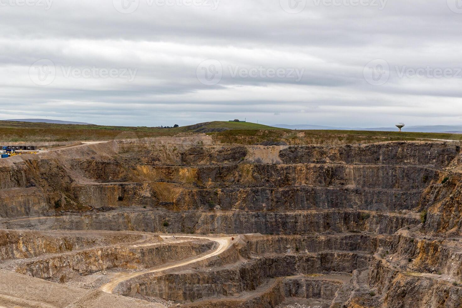 expansief open pit de mijne met kronkelend wegen onder een bewolkt lucht. foto