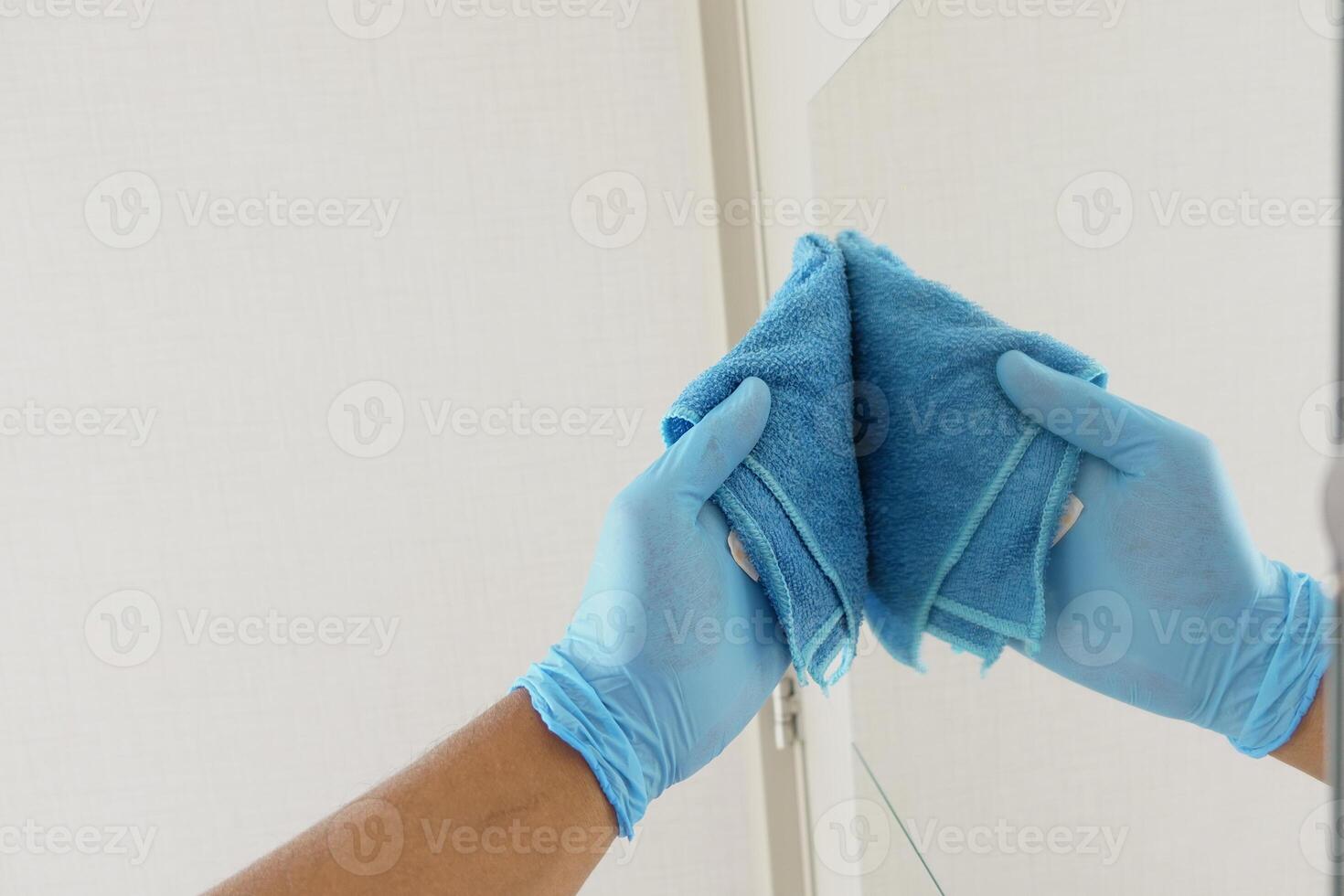 hand- in blauw handschoen schoonmaak venster met groen vod foto