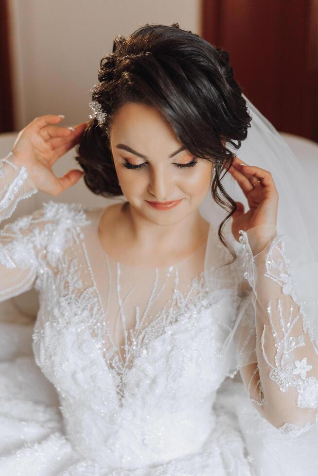 mode foto van een mooi bruid met donker haar- in een elegant bruiloft jurk en verbijsterend bedenken in de kamer Aan de ochtend- van de bruiloft. de bruid is voorbereidingen treffen voor de bruiloft