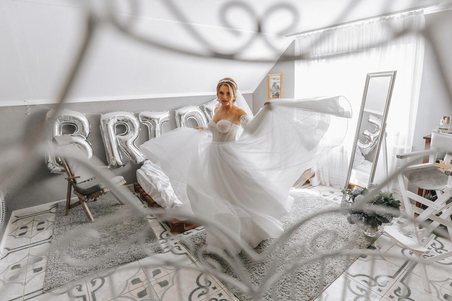 mooi gekruld bruin haar bruid in een wit jurk poses voor een fotograaf, cirkelen de kamer in een mooi jurk met mouwen. bruiloft fotografie, detailopname portret, chique kapsel. foto