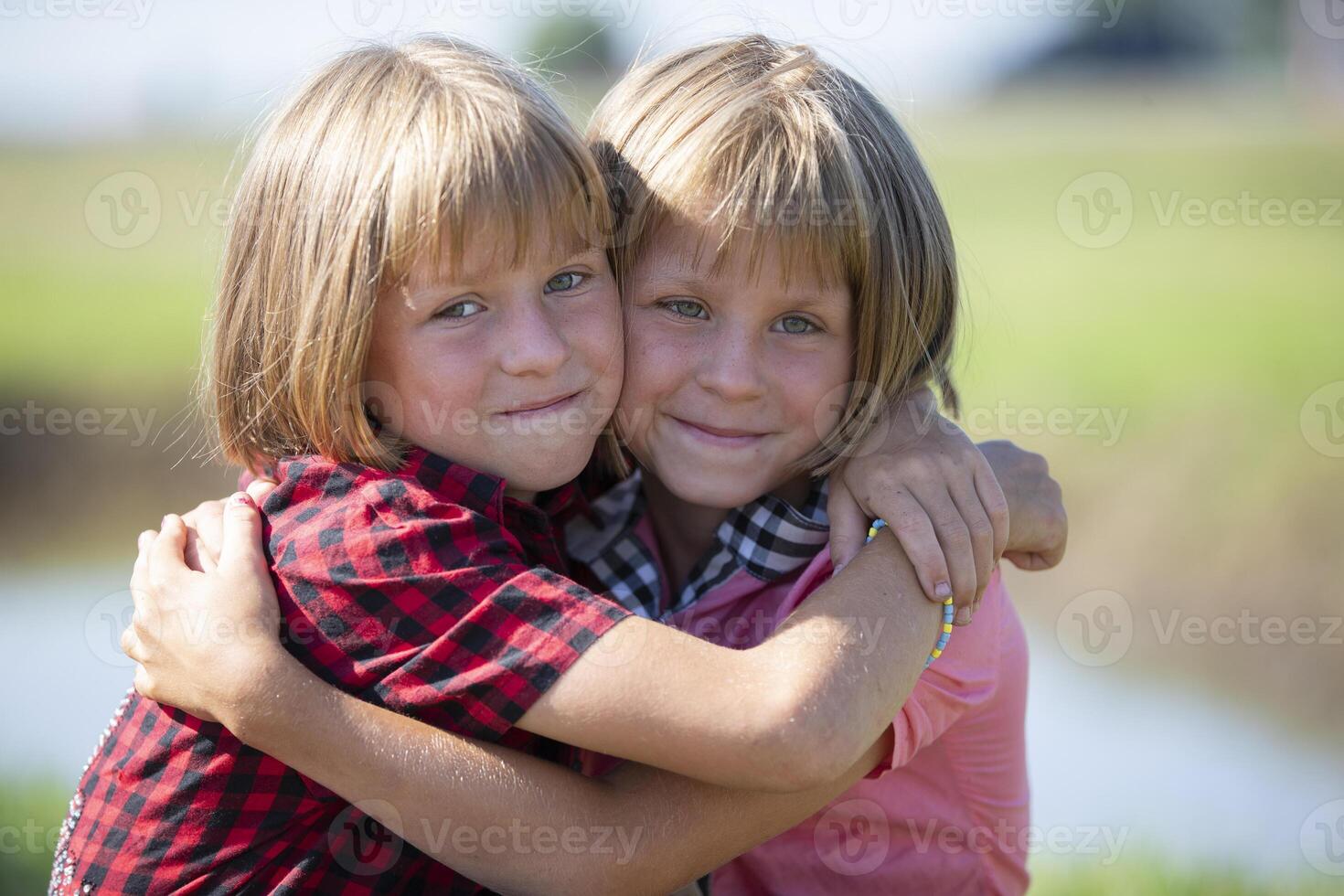 weinig meisjes tweeling zussen knuffel en kijken Bij de camera. foto
