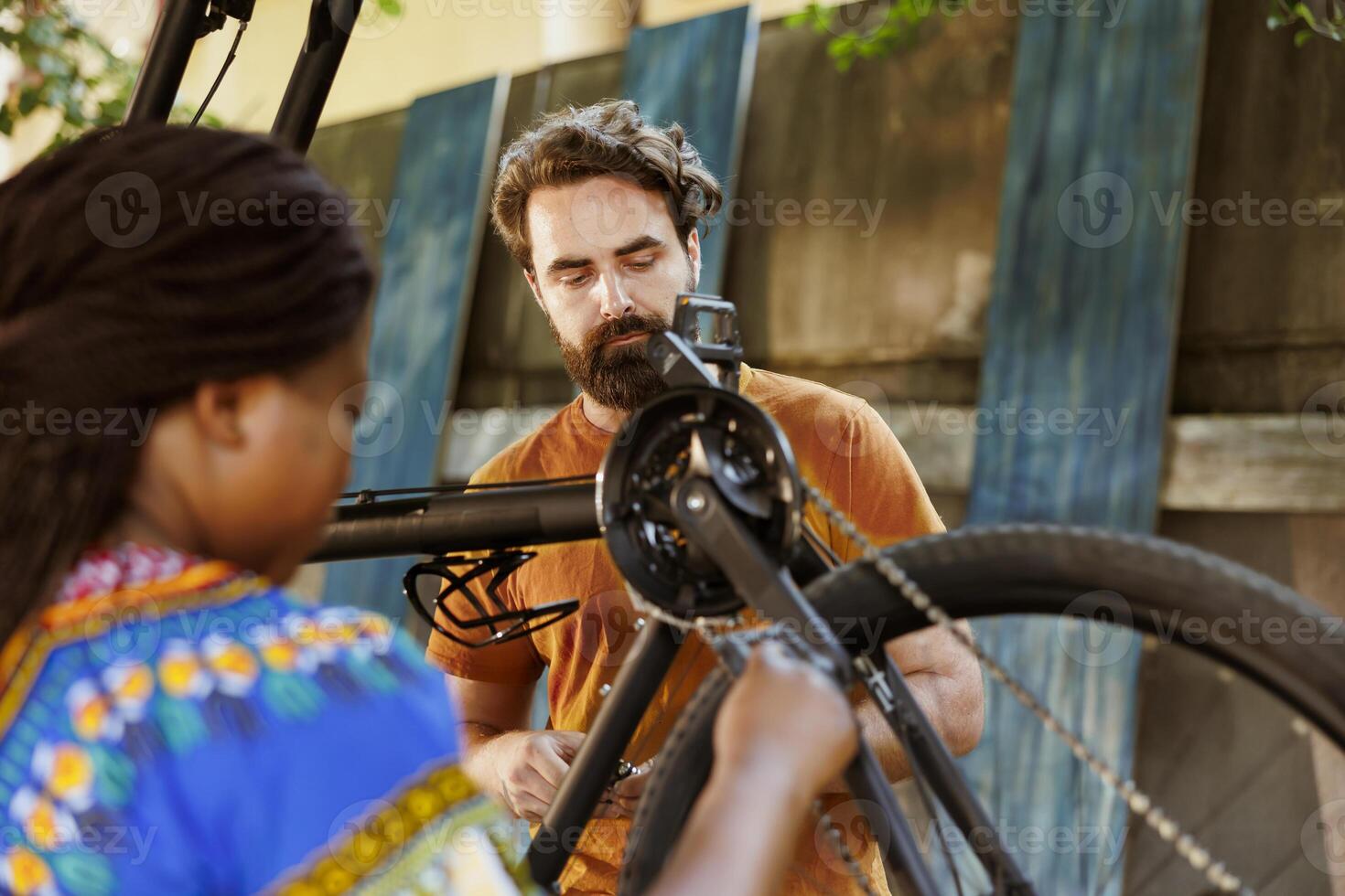 gezond jong multiraciaal paar vaststelling fiets uitrusting met professioneel uitrustingen in tuin. multi-etnisch paar gebruik makend van gereedschap naar reparatie gebroken fiets band en wiel voor zomer vrije tijd wielersport. foto