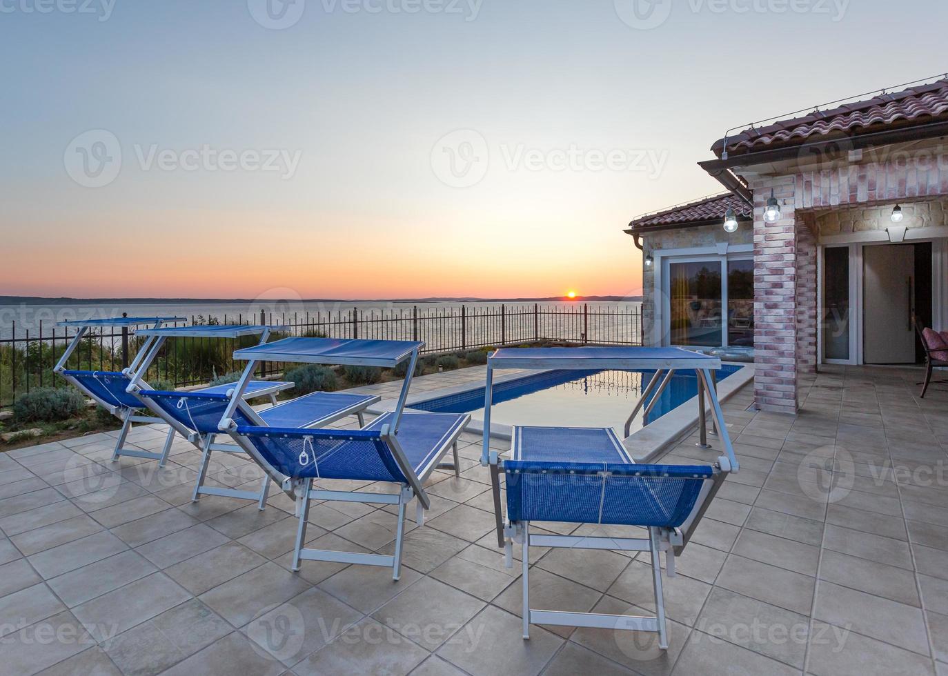 terras met zwembad en ligstoelen bij zonsondergang foto