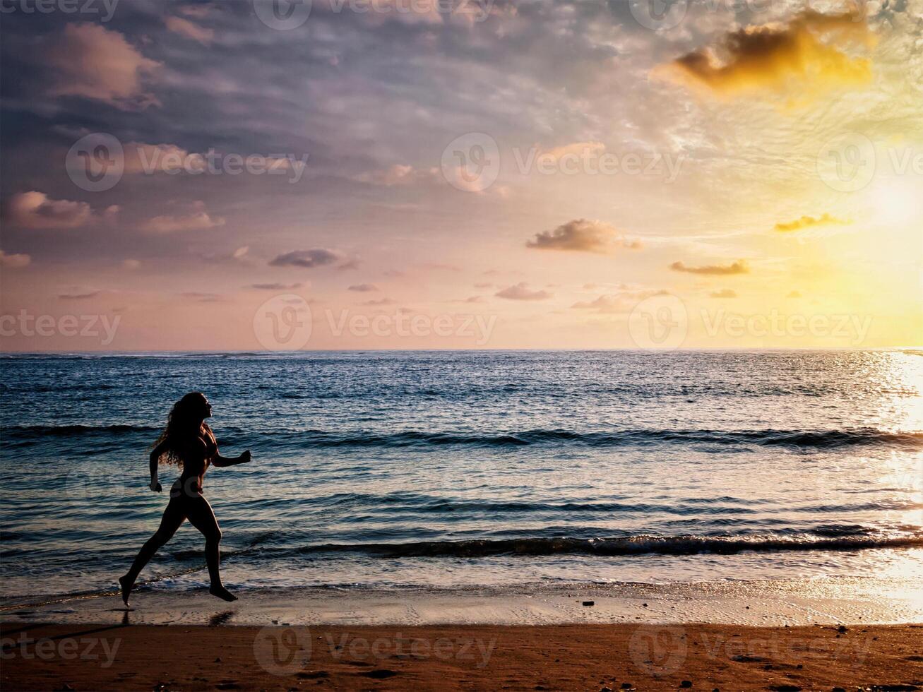 mooi atletisch vrouw rennen langs zee strand in de ochtend- foto