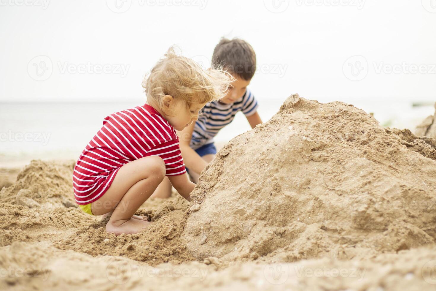 twee weinig jongens spelen Aan zanderig strand. schattig kinderen gebouw zandkastelen Aan strand foto