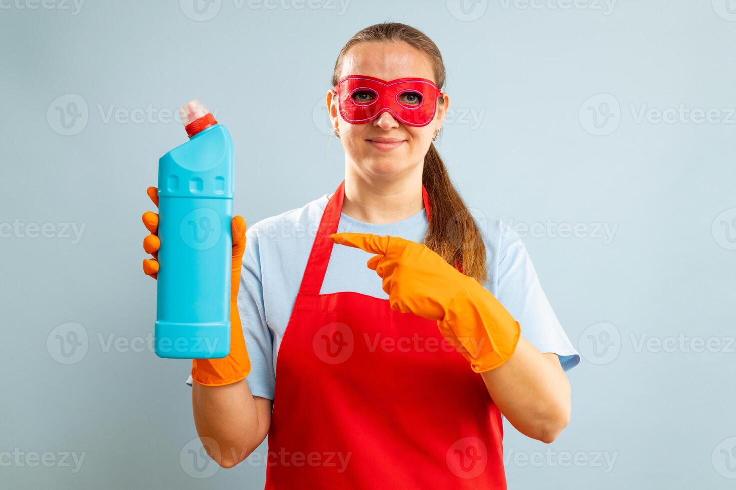 vrouw in rood masker, rubber handschoenen en schort Holding schoonmaak middel fles foto