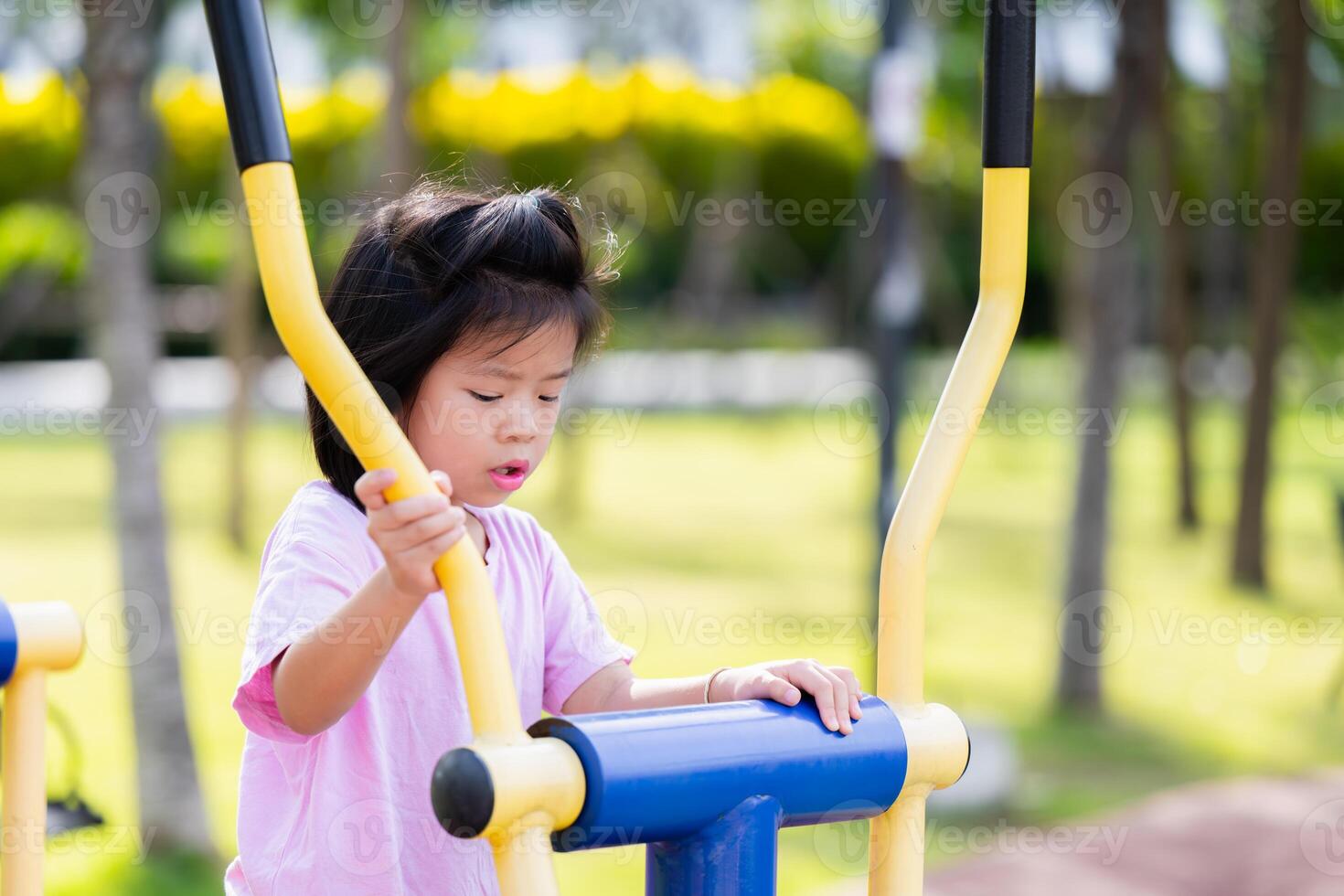 portret van schattig Aziatisch kind aan het leren hoe naar oefening Aan rennen oefening machine Bij een buitenshuis park, jong meisje gebruik makend van oefening fiets in stad speelplaats, in zomer of voorjaar tijd. kind oud zes jaar oud foto