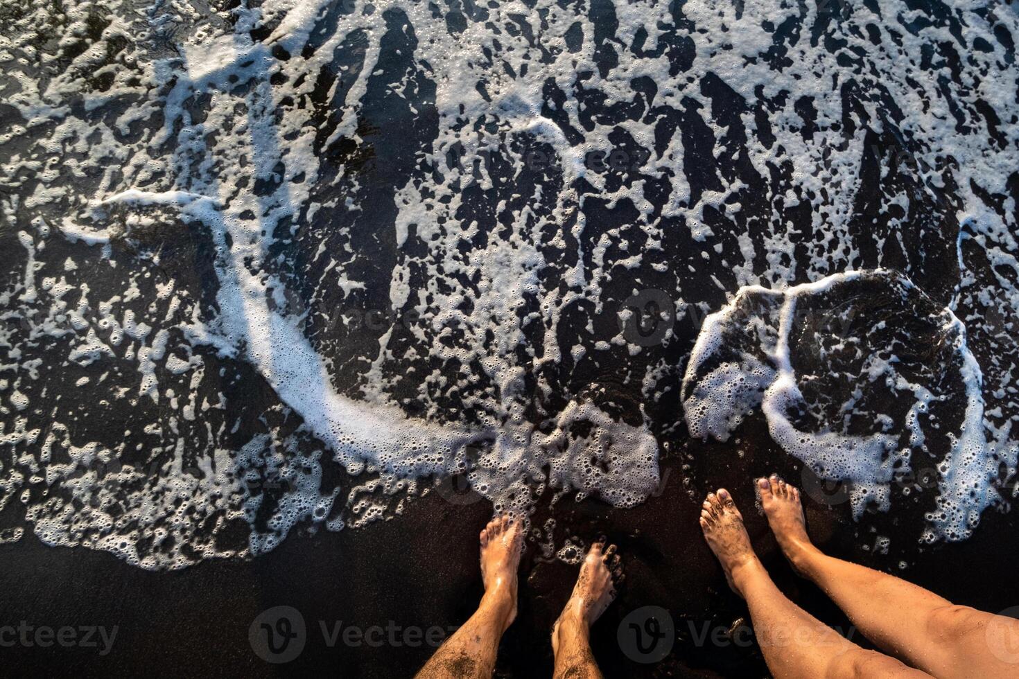 een paar- van voeten Aan de zwart zand in de buurt de oceaan, tenerife, Spanje, kanarie eilanden foto