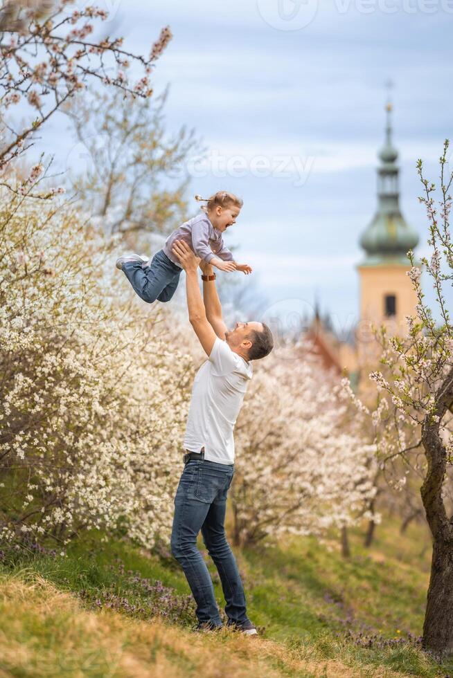 vader en dochter hebben een pret samen onder een bloeiend boom in voorjaar park petrin in Praag, Europa foto