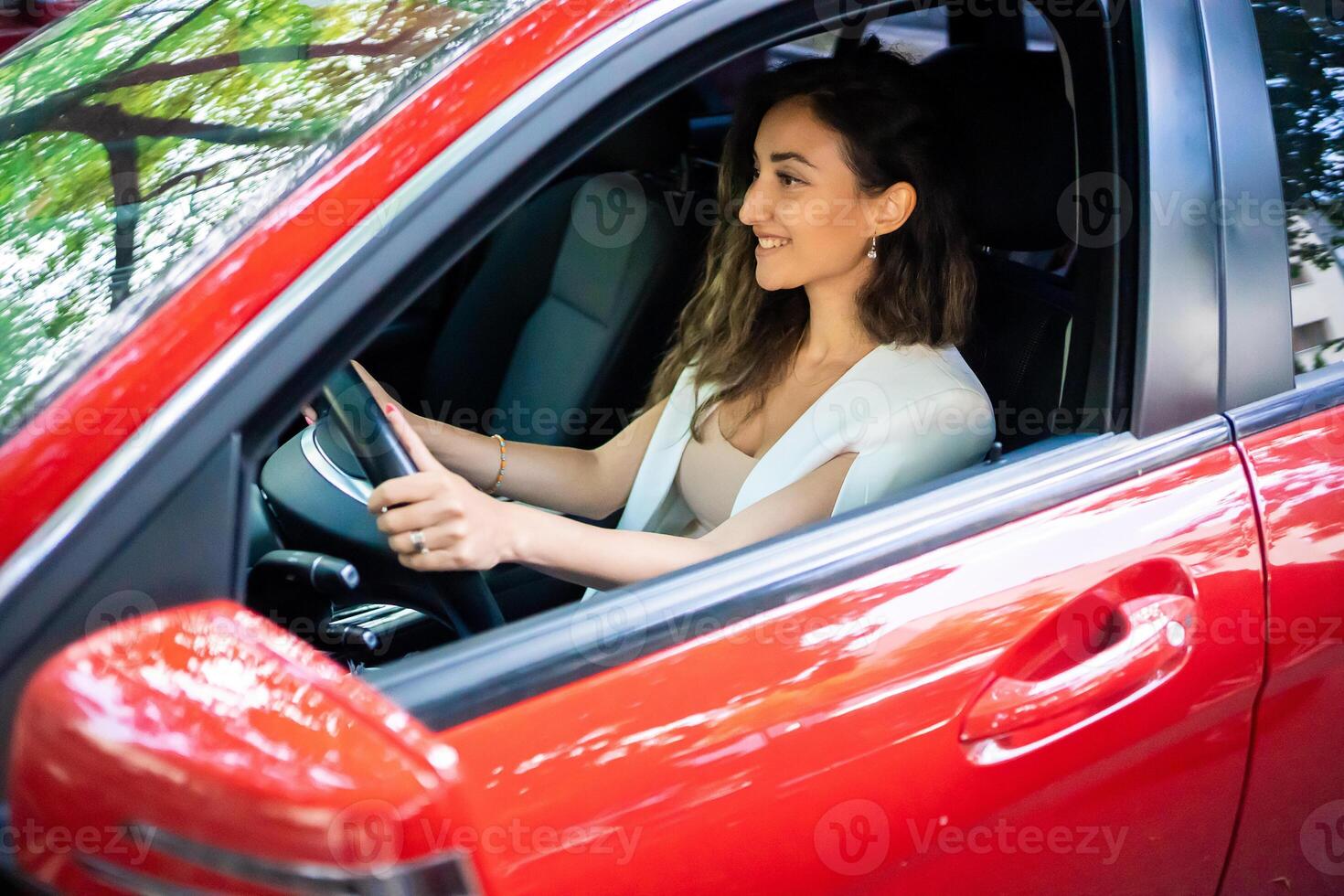 gelukkig glimlachen vrouw bestuurder achter de wiel rood auto. visie door auto venster foto