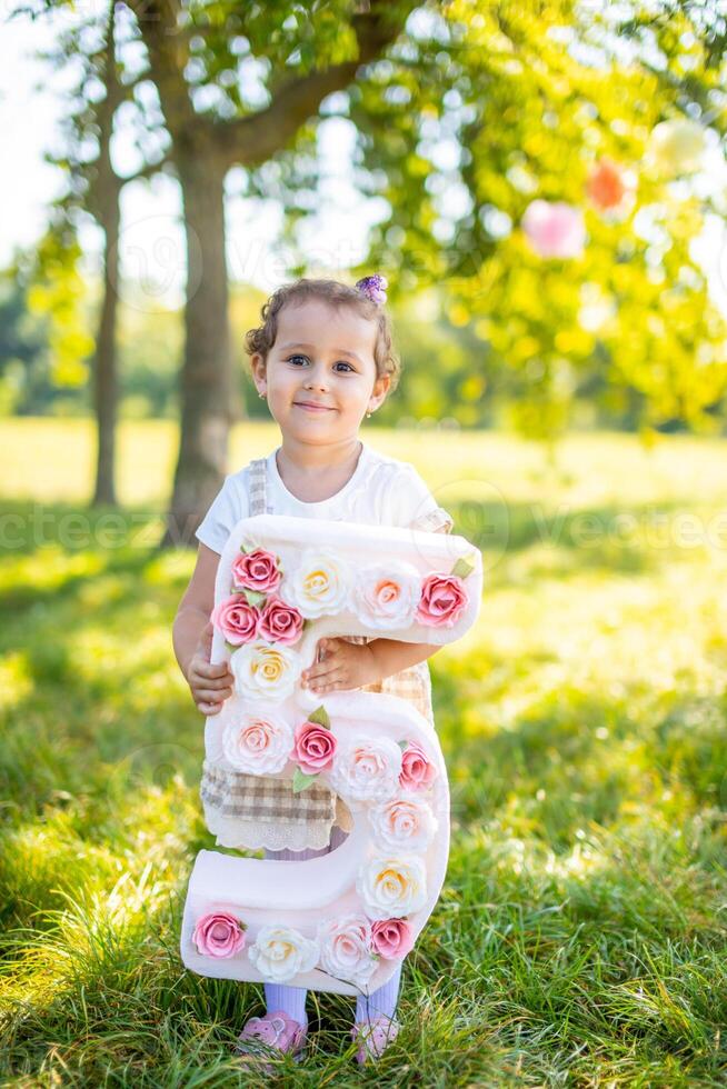 vrolijk meisje hebben pret Aan kind verjaardag Aan deken met papier decoraties in de park foto