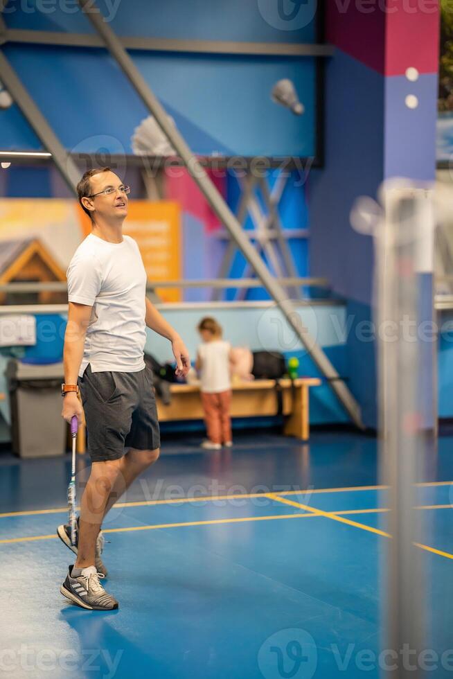 Mens spelen badminton in sport slijtage Aan binnen- rechtbank foto