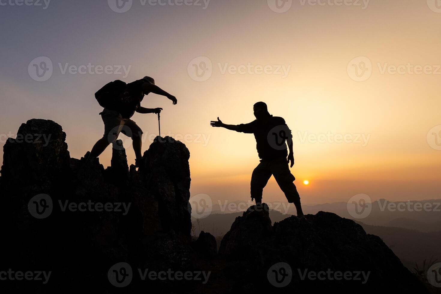 silhouet van de mannen helpen Trekken mensen omhoog van hoog kliffen. foto